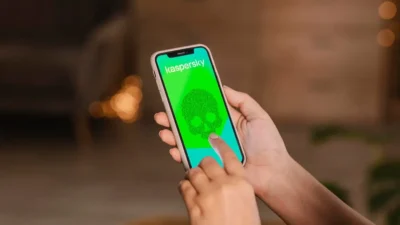 A mobile phone displaying a skull symbol and Kaspersky on a green screen, symbolising the threat of a cyber attack.