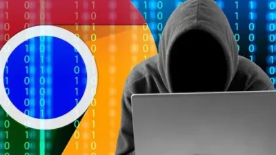 Hacker in a hoodie using a laptop in front of the Google Chrome logo, symbolizing cybersecurity threats and the risk of malicious browser extensions.
