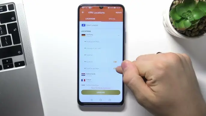 levna VPN | BestSafeVPN.com Smartphone s otevřenou aplikací VPN, zobrazující výběr serverů v různých zemích, včetně Německa, Nizozemska a Francie, vedle ruky uživatele.