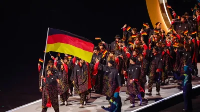 Team Deutschland bei der Eröffnungsfeier der Olympischen Winterspiele 2026 in Mailand – mit Fahne und traditioneller Einmarschkleidung auf der Bühne.